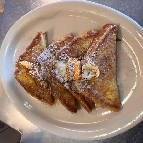 Golden French toast triangles, dusted with powdered sugar and topped with pats of butter.
