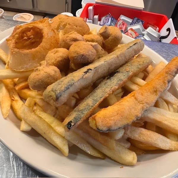 A plate of golden-brown french fries, onion rings, breaded mushrooms, and zucchini sticks.