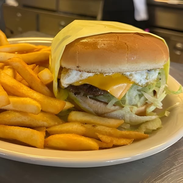 Jim's Burgers & Eggs burger with cheese, fried egg, lettuce, and fries on a white plate.